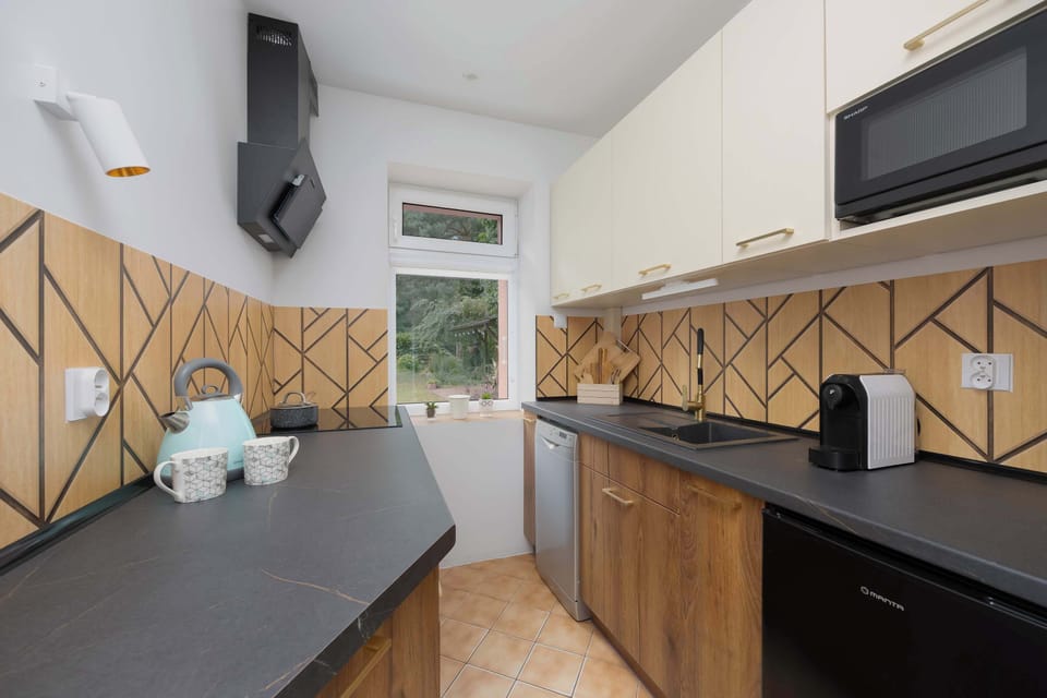 Modern kitchen with wood-accented backsplash and dark countertops.
