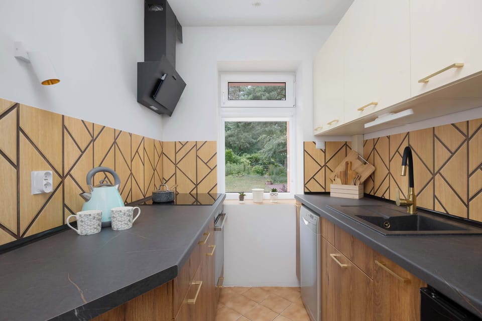 Modern kitchen with wood-accented backsplash and dark countertops.