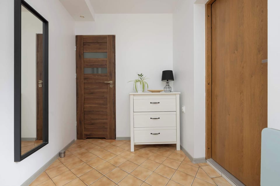 Entryway with a small white dresser and wooden doors.