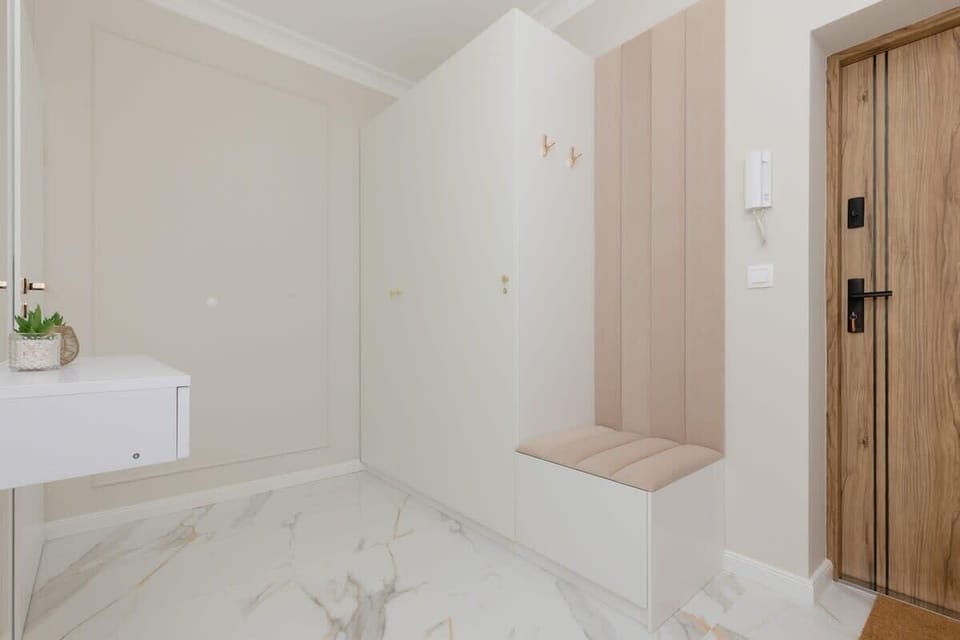 A hallway with built-in storage, a wooden bench, and a mirror, creating a functional entrance.
