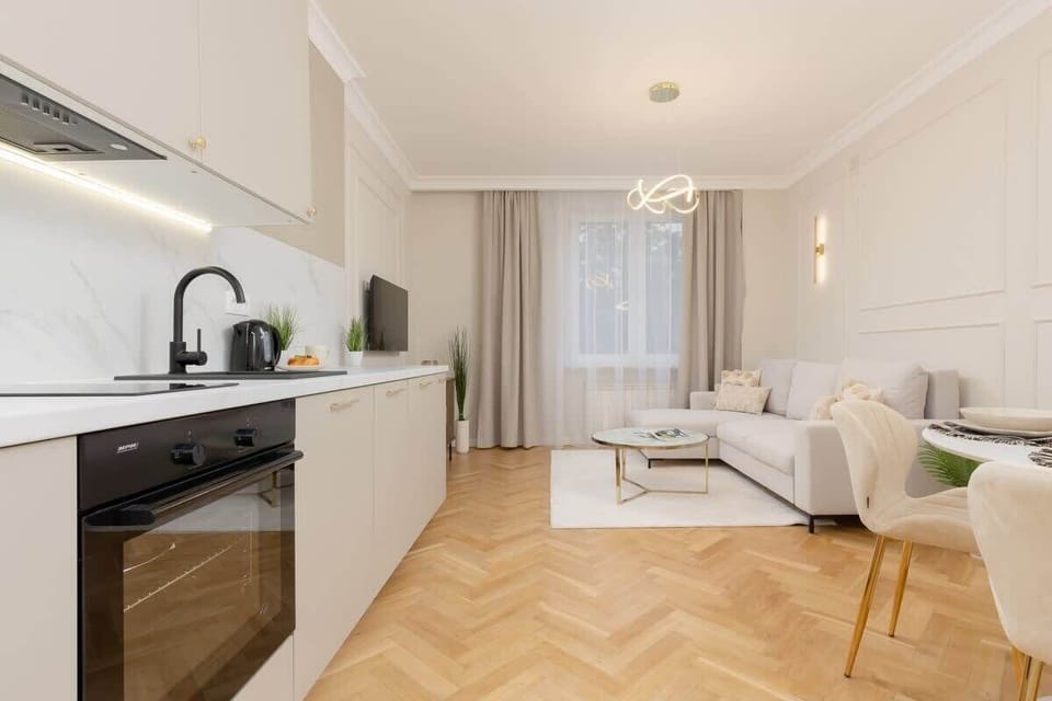 A modern kitchen area with sleek cabinetry, built-in appliances, and a marble backsplash.
