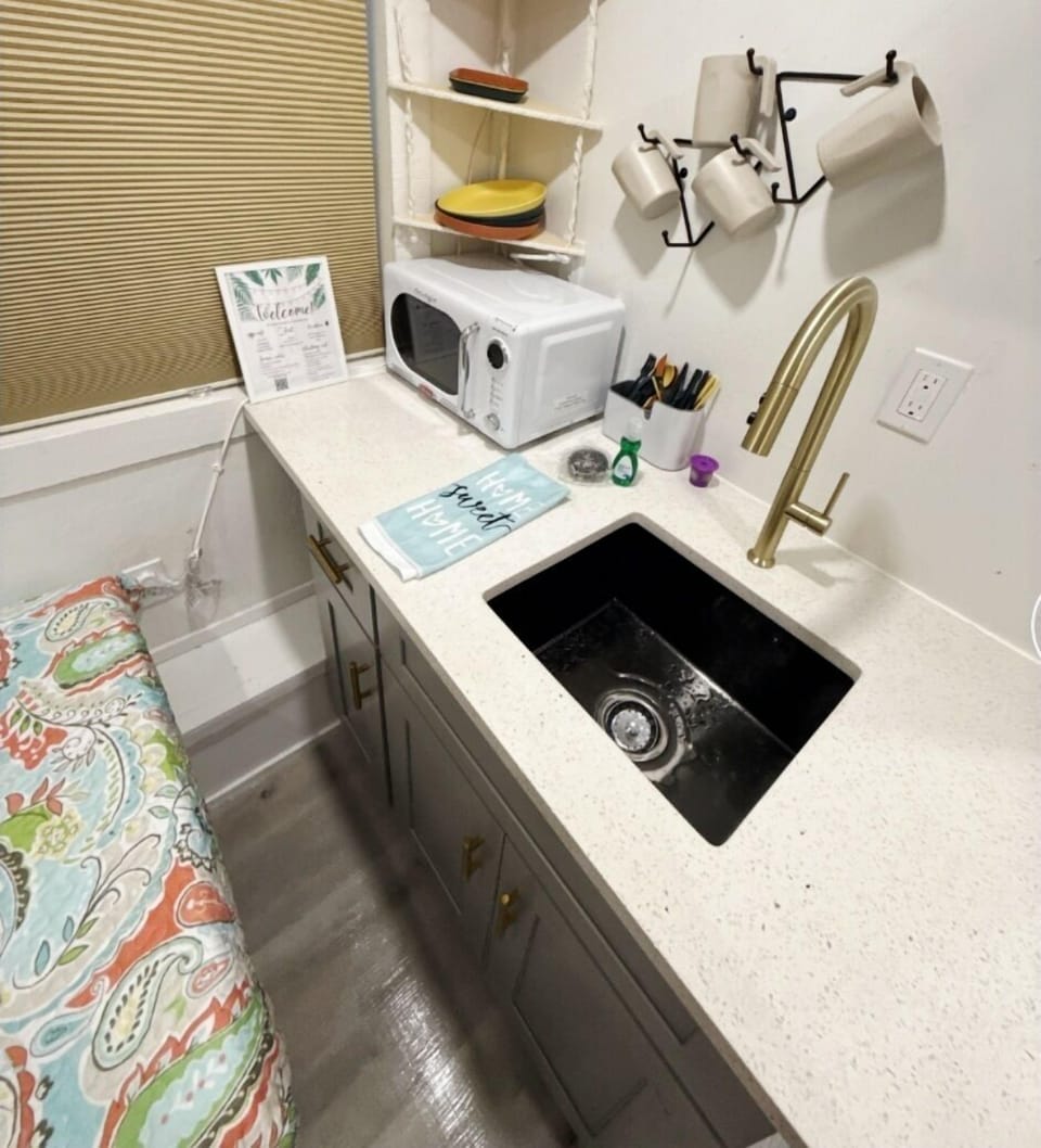 Kitchenette pictured with microwave, sink, single burner hot plate and basic cookeare/dishes