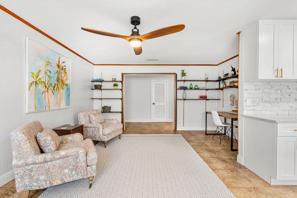 Bright sitting area with soft chairs and shelves for books and decor.