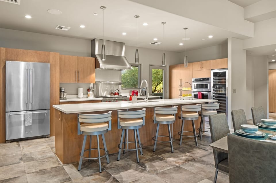 Kitchen features include a Wolf gas range, oversized island with bar seating, dual-zone wine fridge, and Keurig coffee maker