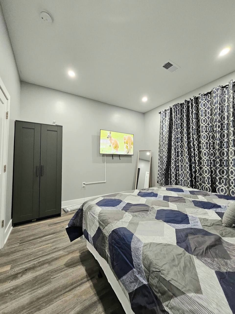 Bedroom 5 offers a plush king bed, smart tv, mirror, closet, and a large window.