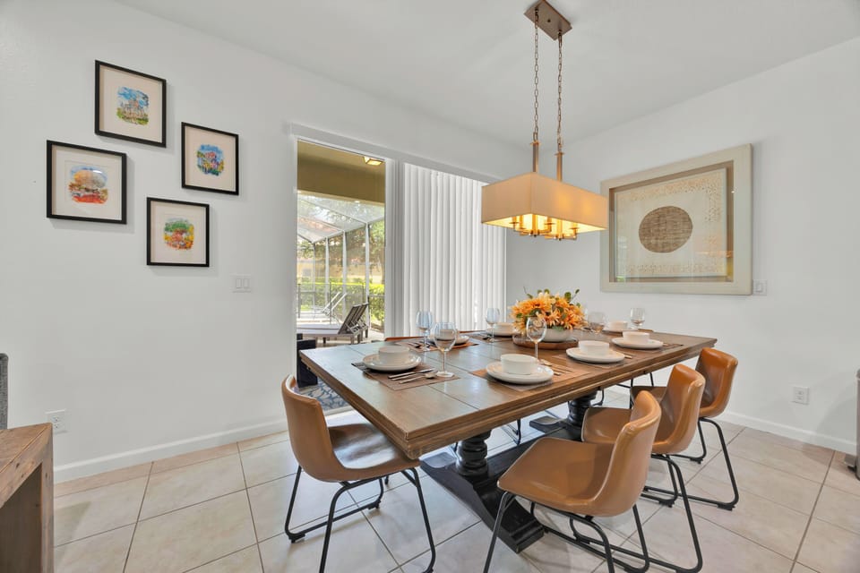 Gather in style 🍽️ This bright Florida dining room seats 8 comfortably around a rustic-chic table, surrounded by subtle Disney-inspired artwork and natural light—perfect for family meals, game nights, or toasting a magical day at the parks.