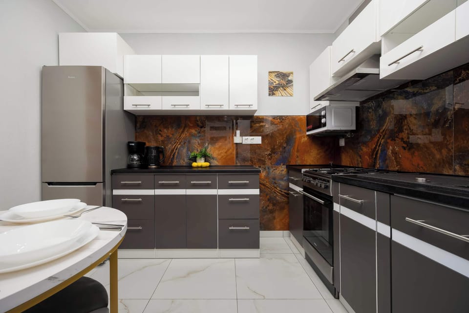 A functional and sleek kitchen space with a gold-accented round table and black cabinetry.