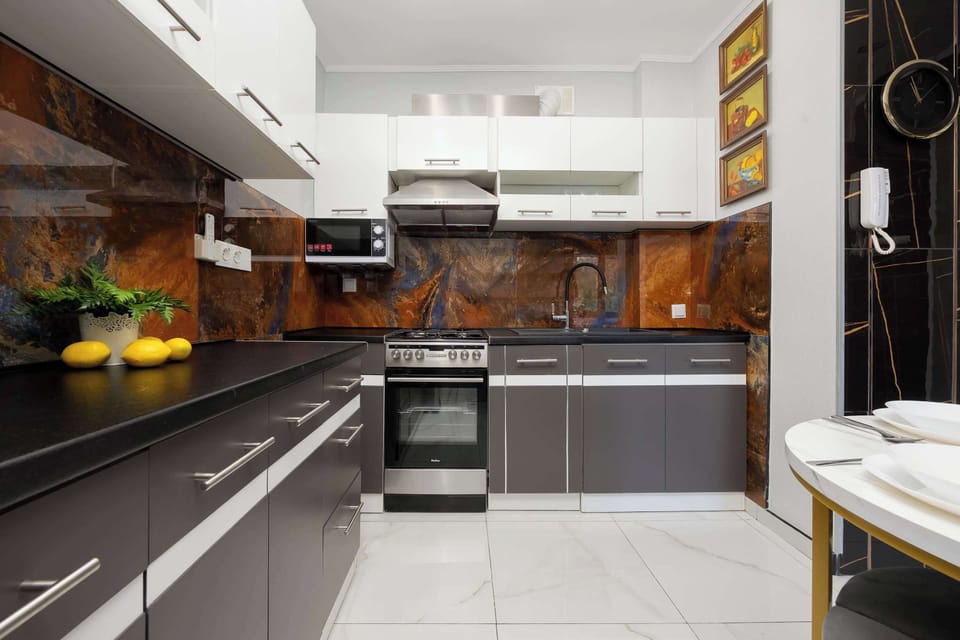 A sleek kitchen with glossy white upper cabinets, dark lower cabinetry, and wooden backsplash panels.