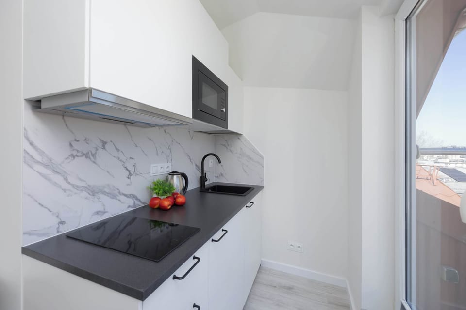 A compact kitchen corner with white cabinets, gray countertop, and marble backsplash.