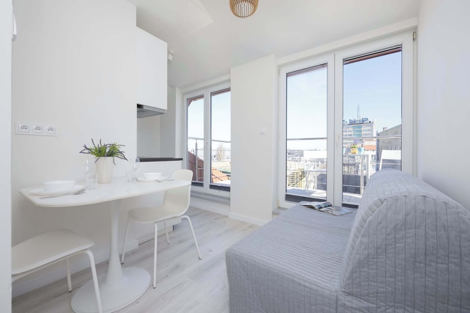 A seating area with a gray couch next to a set of large windows, offering a view of the city skyline.