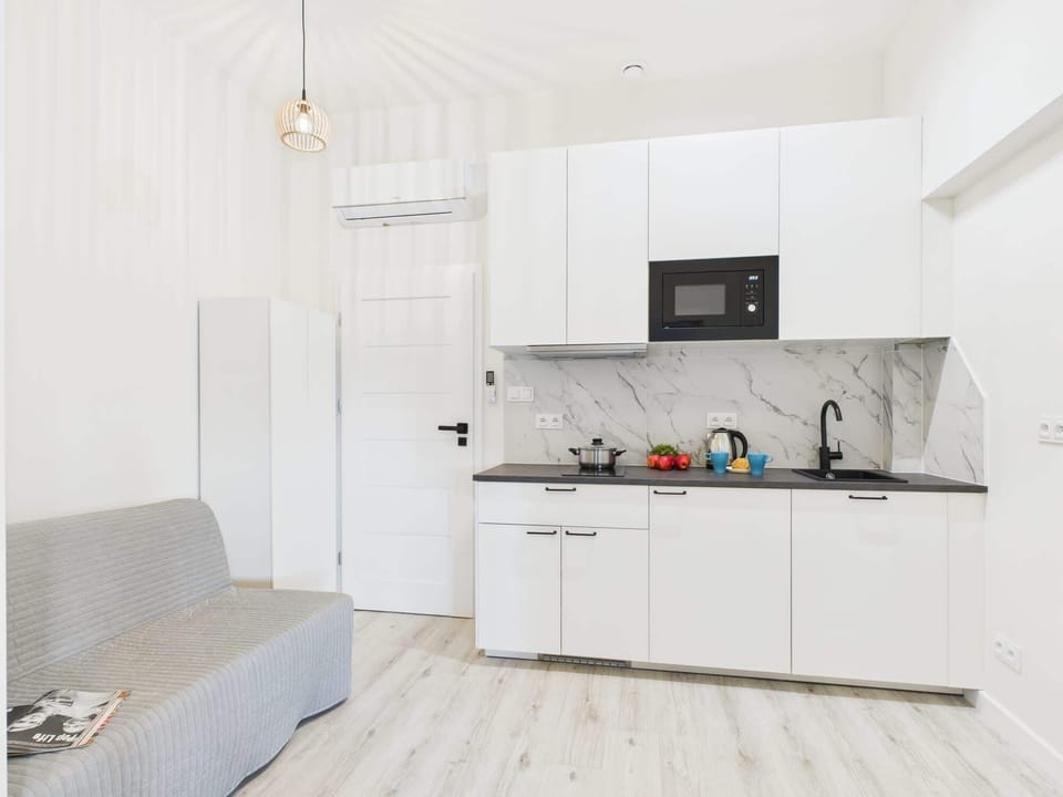 An open-plan living space with a gray chair and a white kitchen. It's a functional area with cozy seating and modern finishes.