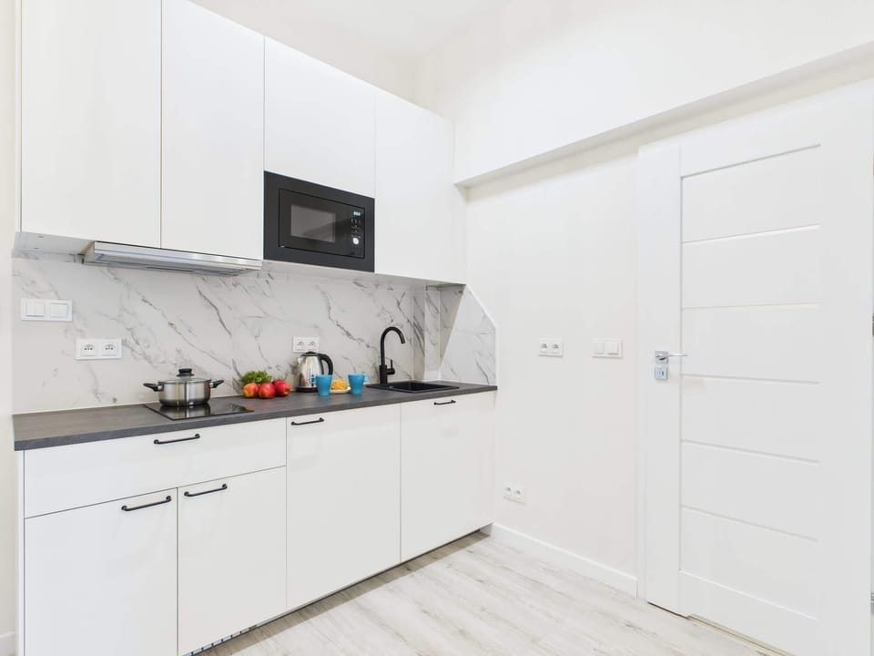A compact white kitchen with modern cabinets and integrated appliances. The layout is efficient with a clean, seamless look.