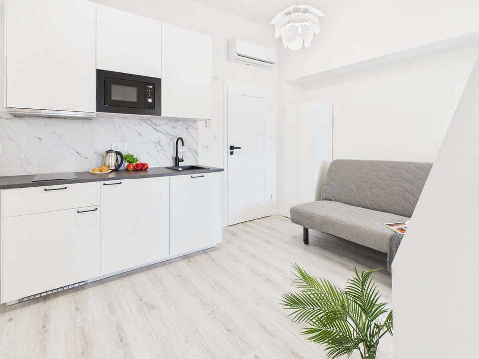 A clean and bright living space that opens up into the kitchen. A plant and decorative details add life to the neutral design.