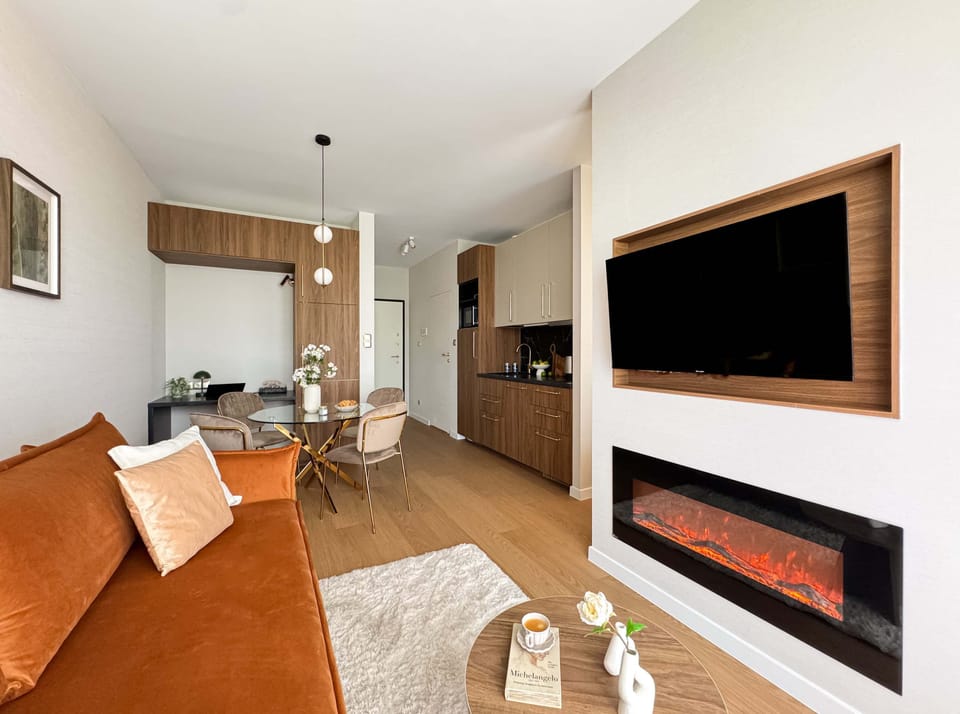 A bright and spacious living room with two wall-mounted fireplaces and a comfortable seating area. Large windows let in plenty of natural light.