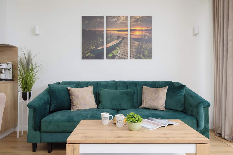 A cozy living room with a comfortable green sofa and large windows letting in natural light.