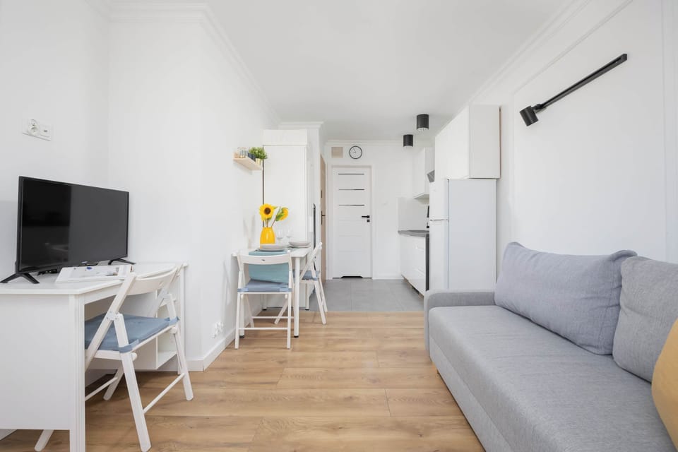 Experience the bright and airy ambiance of this studio, thoughtfully designed with a cozy seating area, a charming dining space adorned with sunflowers, and a functional kitchenette, all bathed in natural light.