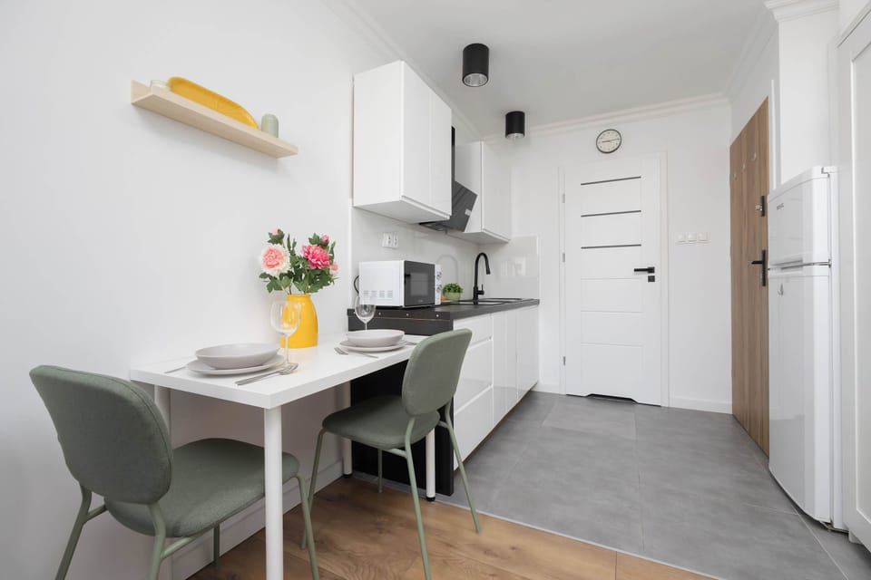 A kitchen and hallway view with a door in the background and subtle lighting above the cabinets.

