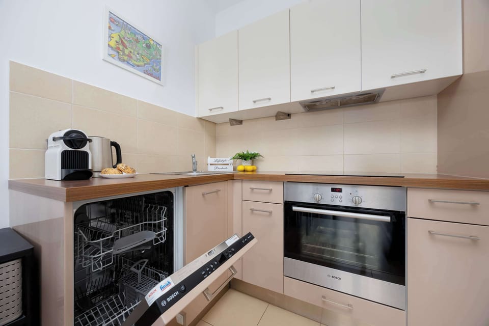 A modern kitchen with white countertops, stainless steel appliances, and beige cabinetry. The design is practical and stylish, offering ample space for cooking.
