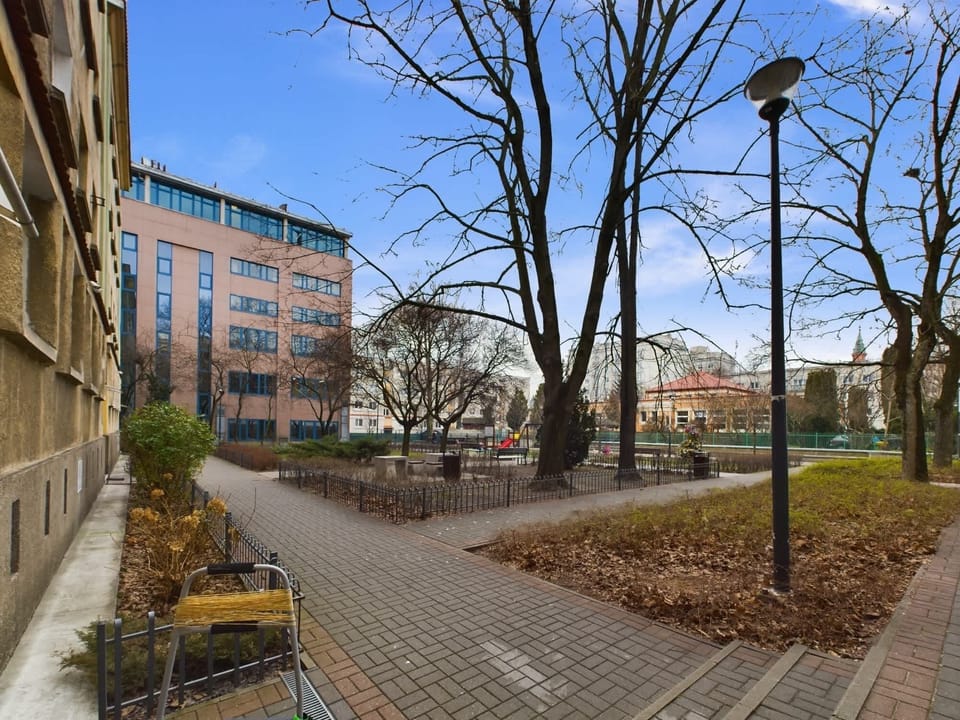 There are green areas with walking paths next to the building.