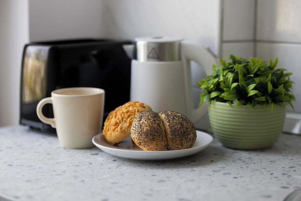 A side view of the kitchen countertop with breakfast setup including cups, rolls, and greenery.
