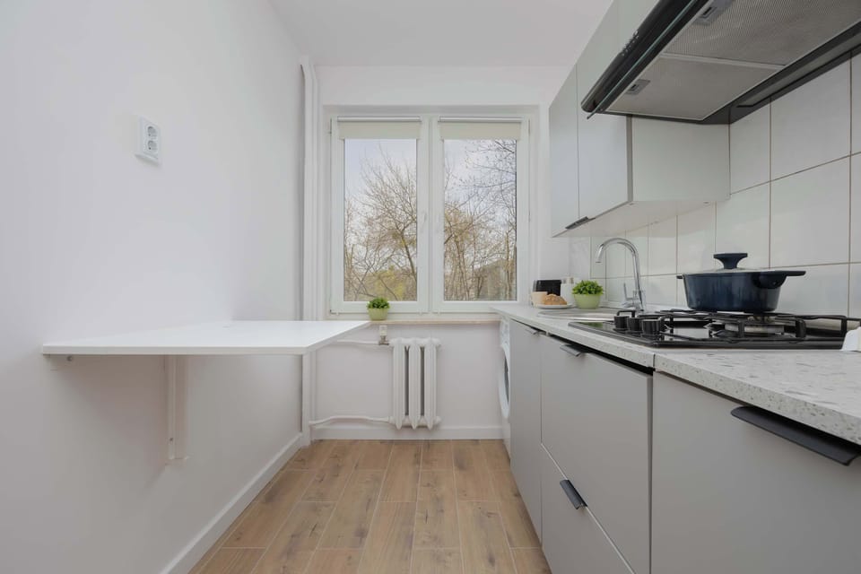 A corner of the kitchen featuring a stove, kettle, and upper cabinets with clean, white finishes.
