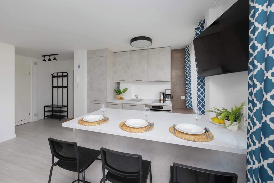A modern kitchen with a white island, pendant lights, and black dining chairs, creating a clean and open space.