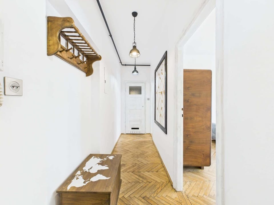 Hallway with wooden details, coat hangers, and a minimalist design leading into the studio apartment.