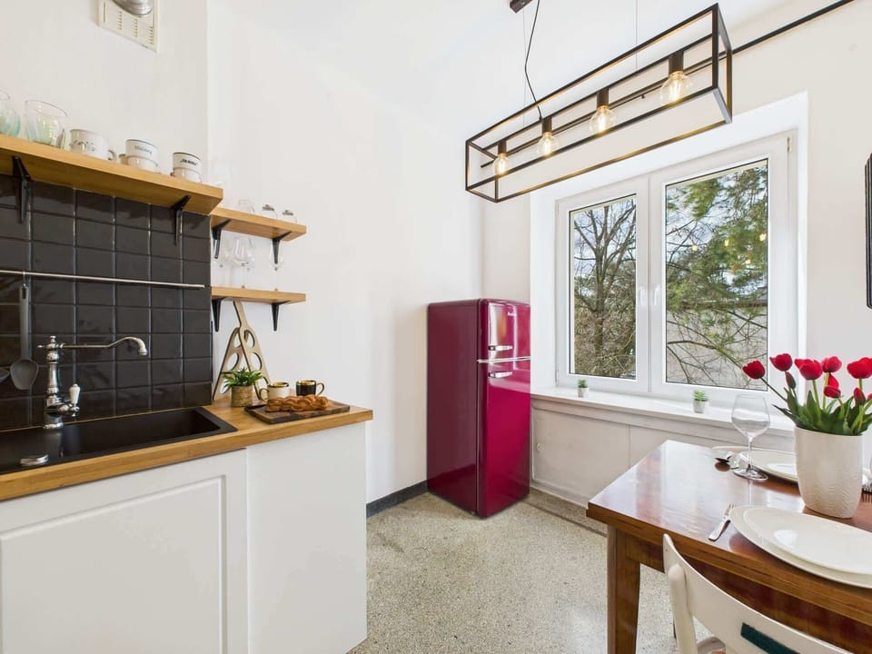 Modern kitchen space featuring black tile backsplash, open wooden shelves, and essential appliances.