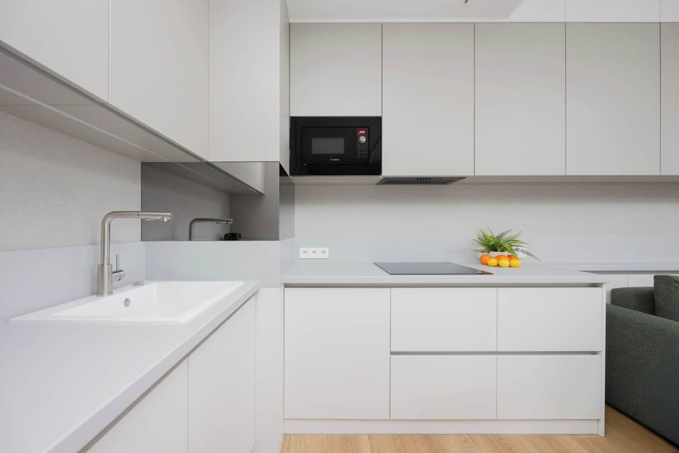 A minimalist kitchen with white cabinetry, built-in appliances, and clean lines.