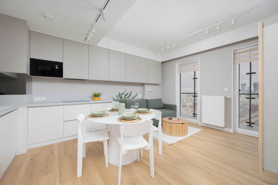 A bright and stylish living room with a comfortable green sofa and a small dining table for four.