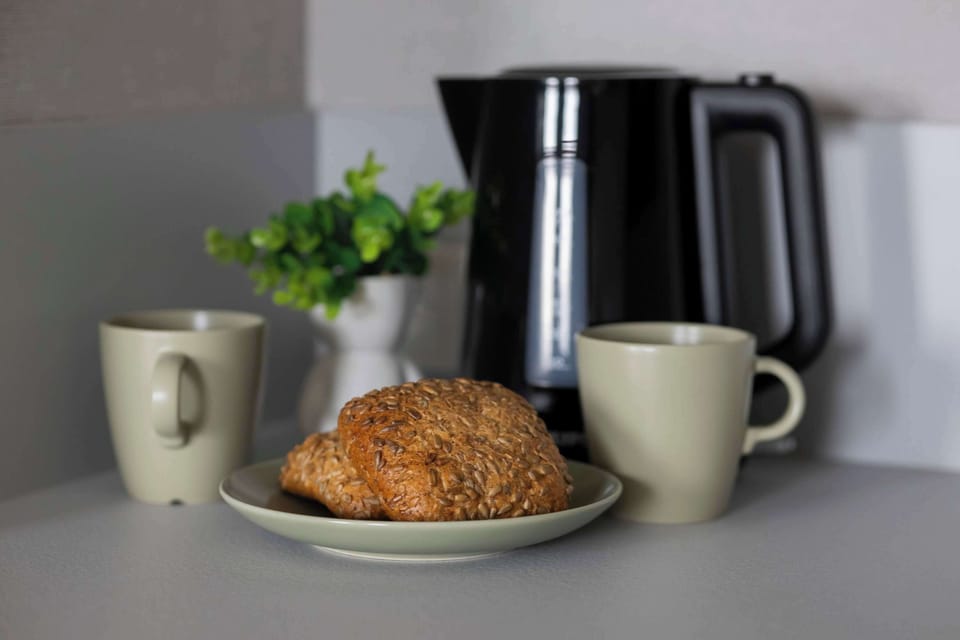 A close-up of a breakfast scene with coffee, croissants, and fresh greenery on the countertop.