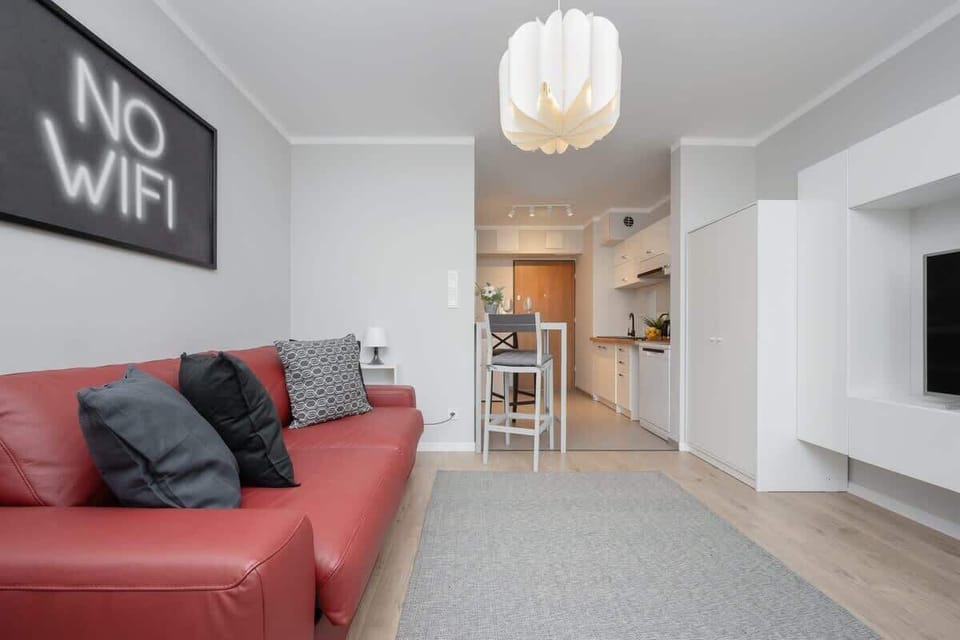 Another perspective of the living space, featuring the red sofa, "No WiFi" artwork, and a well-lit ambiance.

