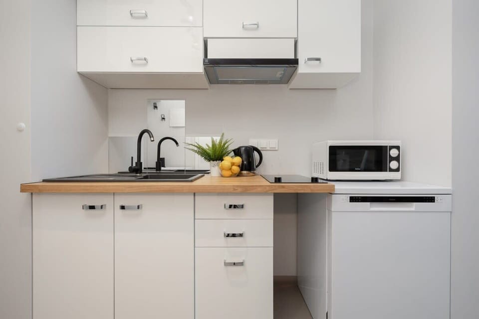 A compact kitchen with white cabinetry, a wooden countertop, and essential appliances like a microwave and stovetop, offering a functional cooking space.

