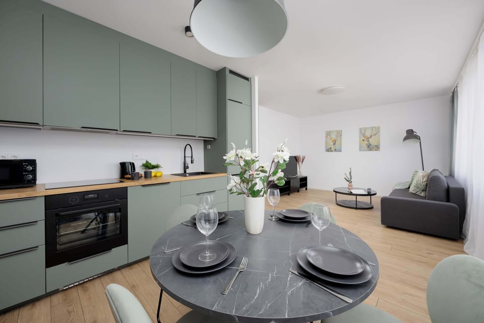 Kitchen with dining area and light green cabinets – Scandinavian-inspired design and functionality.