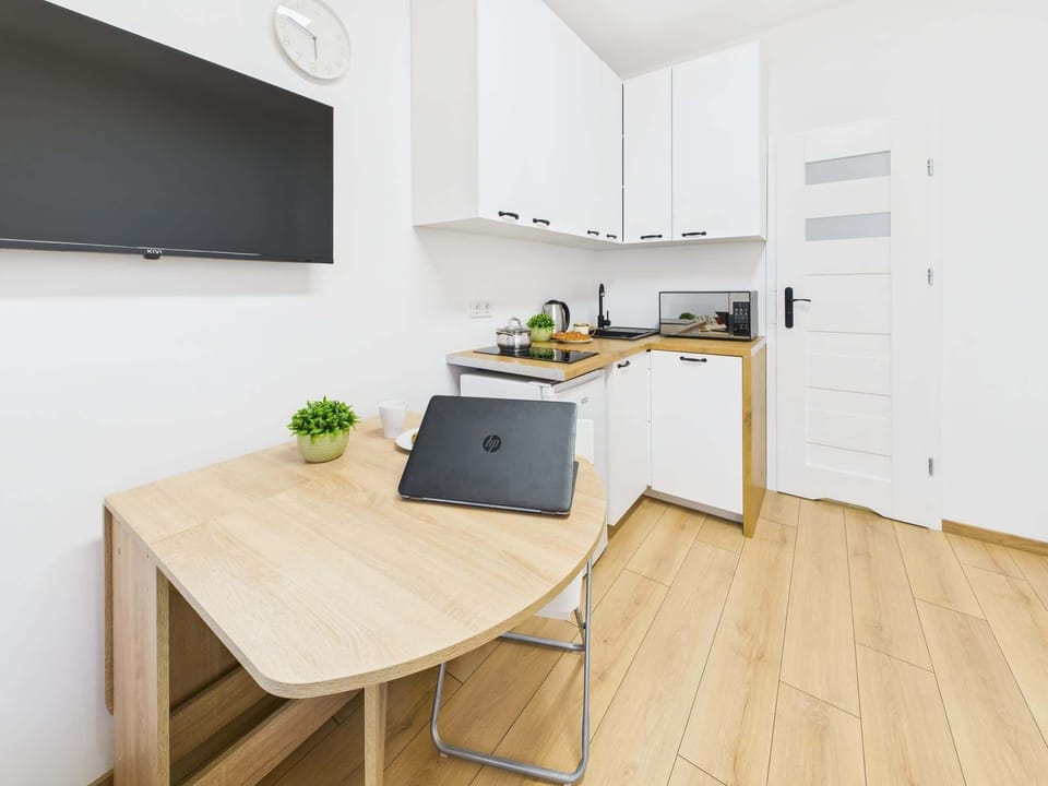 A fully equipped kitchen showcases a modern design. White cabinets and wooden countertops contribute to a clean and elegant look.