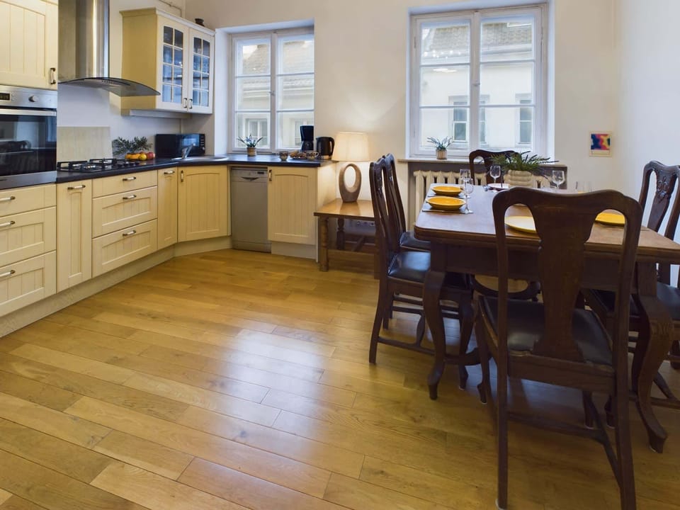 A well-lit dining area with a wooden table and chairs. The space is connected to the kitchen, making it ideal for family meals.