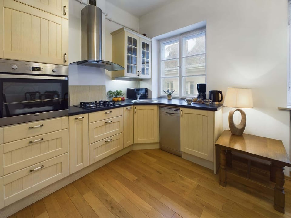 A bright kitchen with wooden cabinets, modern appliances, and a dining table set for a meal. The room has a warm and inviting atmosphere.