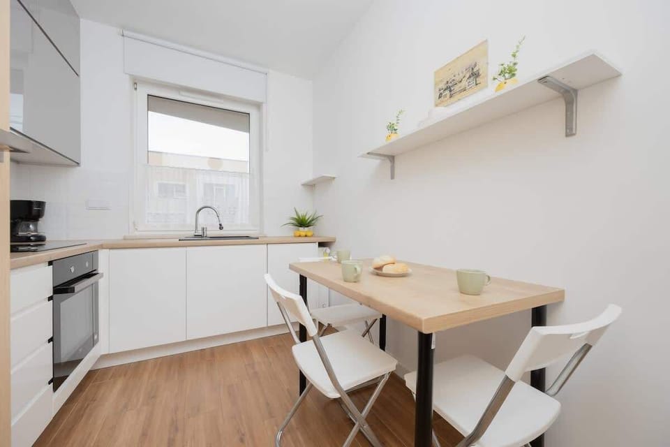 A functional kitchen with white cabinetry, a wooden countertop, and white bar stools. Open shelving adds to the practicality.