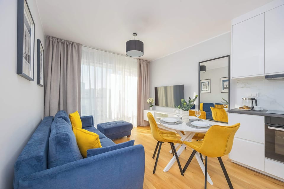 Another angle of the living room, showing the bright windows, the sofa, and the dining table.
