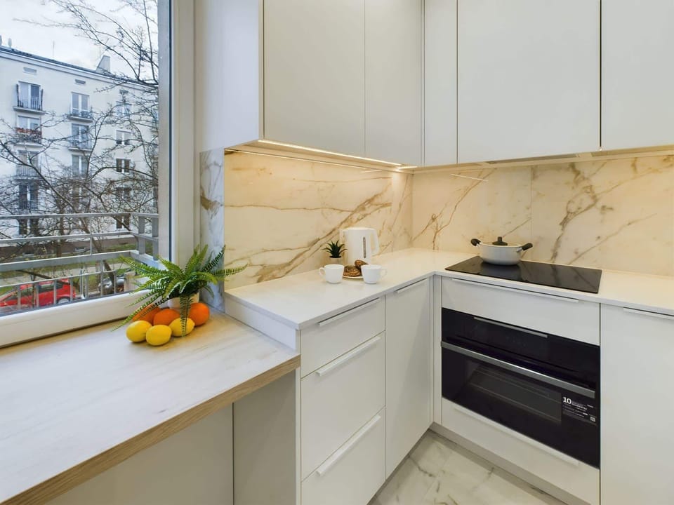 A modern kitchen with white cabinets, marble-style backsplash, and built-in appliances for a sleek look.