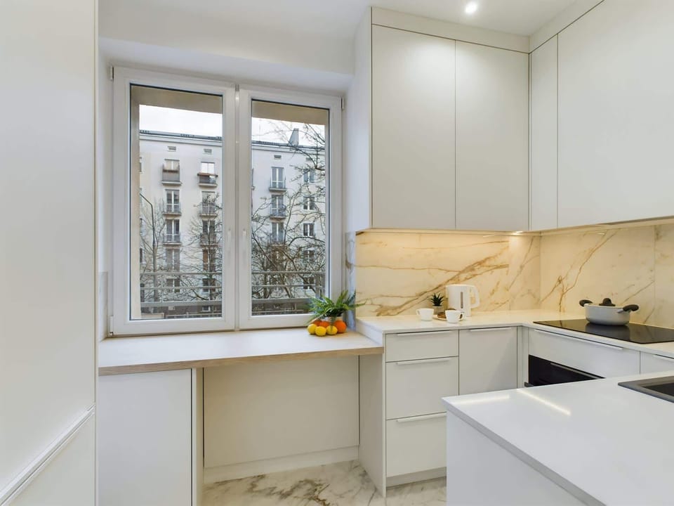 A modern kitchen with white cabinets, marble-style backsplash, and built-in appliances for a sleek look.