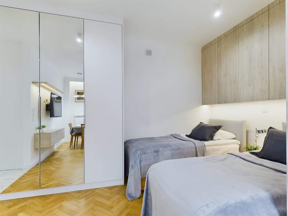 A combined living and sleeping space featuring a comfortable bed, mirrored wardrobe, and a cozy atmosphere.