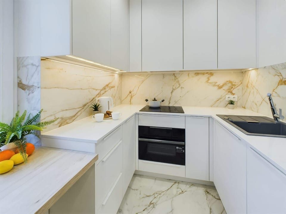 A modern kitchen with white cabinets, marble-style backsplash, and built-in appliances for a sleek look.