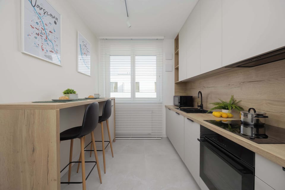 A compact yet stylish kitchen features wood accents, high stools, and ample lighting.