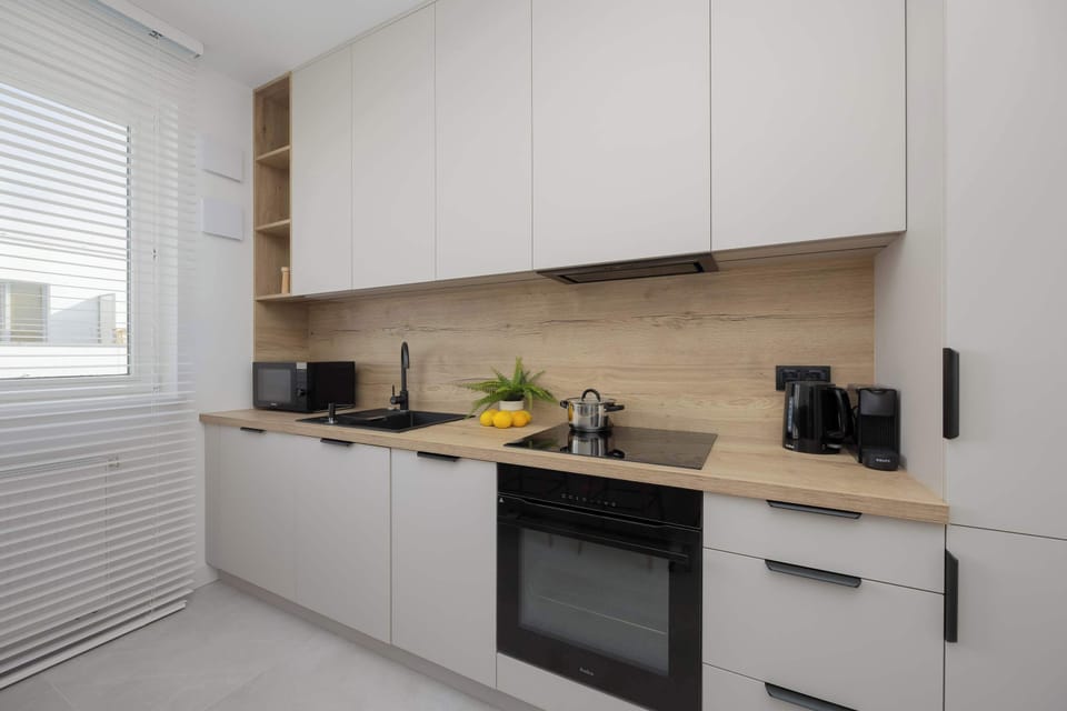 A minimalist kitchen with white cabinetry and contrasting black appliances maximizes style and efficiency.

