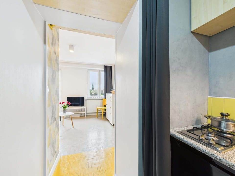 A well-lit entryway with a large mirror, a yellow chair, and a coat hanger, providing a welcoming space.