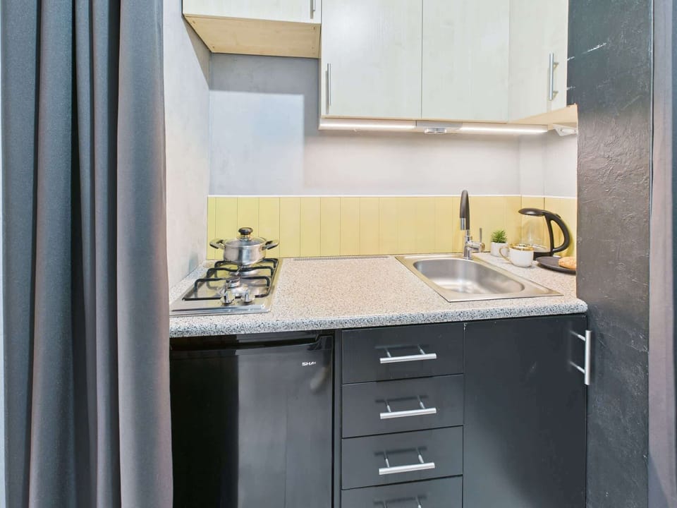A close-up of the kitchen area, highlighting the sink, stovetop, and stylish backsplash.