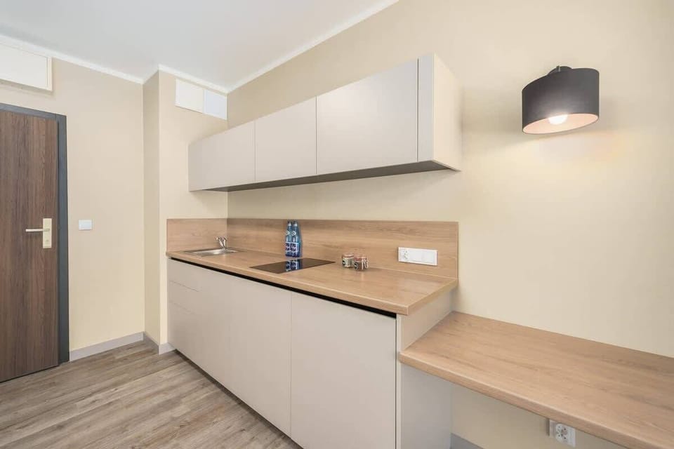 A modern kitchenette with white cabinetry, wooden countertops, and integrated appliances for a sleek design.
