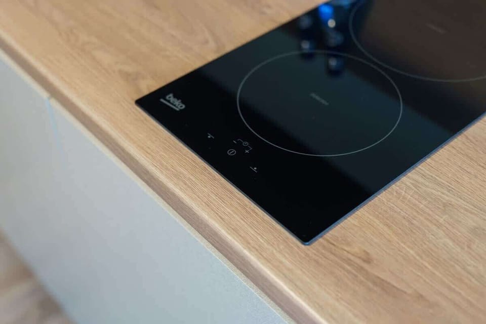 A black induction cooktop on a wooden countertop, blending style with functionality in the kitchen space.






