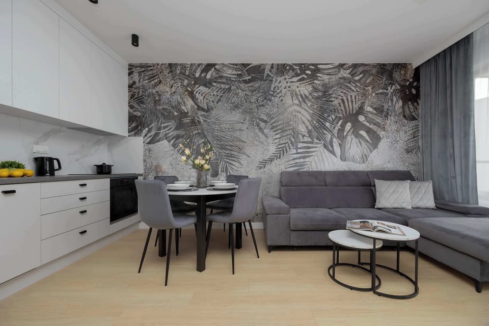An open-plan living area with a kitchen, dining set, and artistic wallpaper creating a stylish atmosphere.